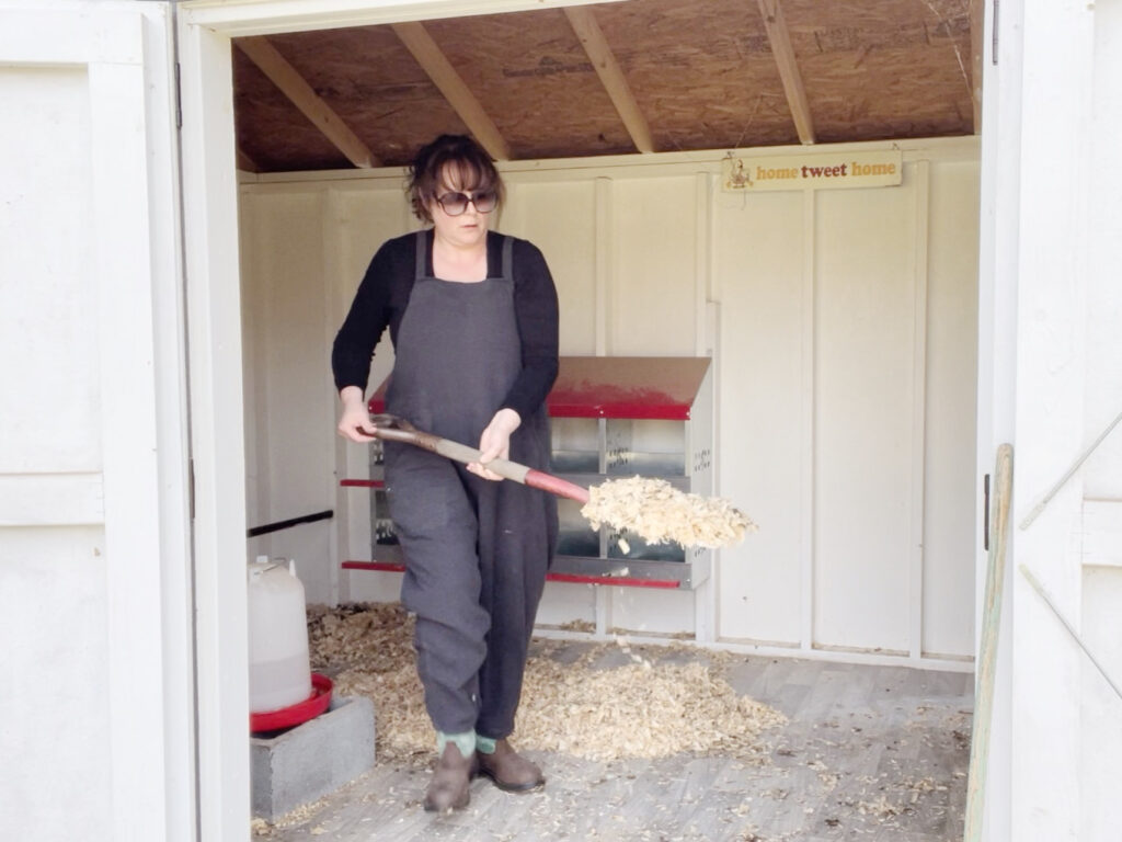 a woman cleaning a chicken coop