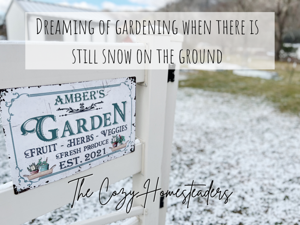 a garden sign on fence with snow on the ground